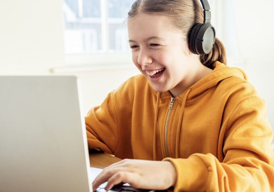 Happy school-age girl participates in a live online class